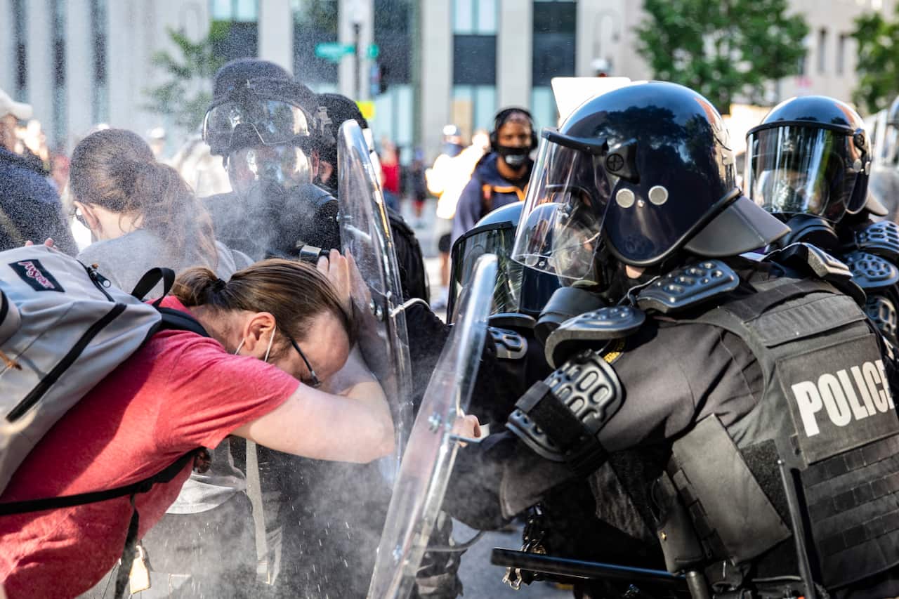 Officers pepper spray a protester while pushing him back during a demonstration in Washington DC over the death of George Floyd.