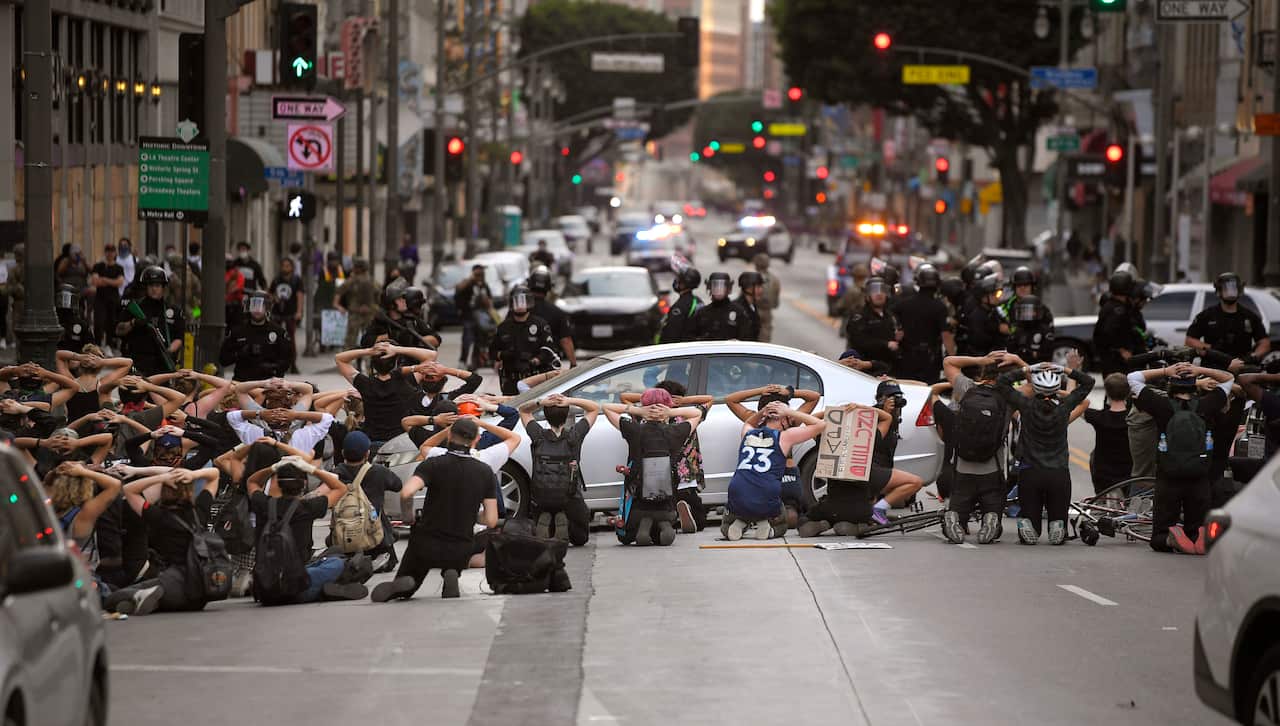 Demonstrators in Los Angeles put their hands behind their head before being taken into custody after breaking curfew. 
