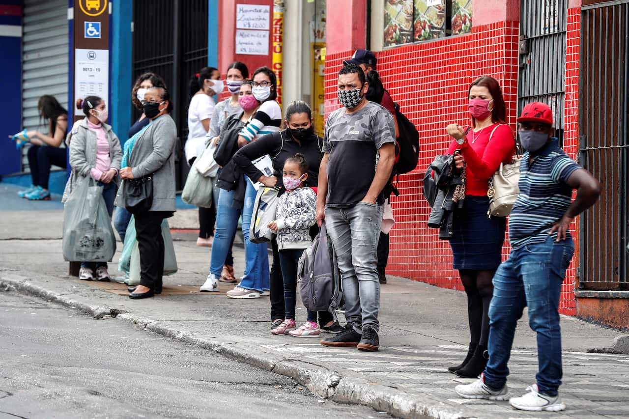 People wait in line to take a public transport bus in Sao Paulo, Brazil.