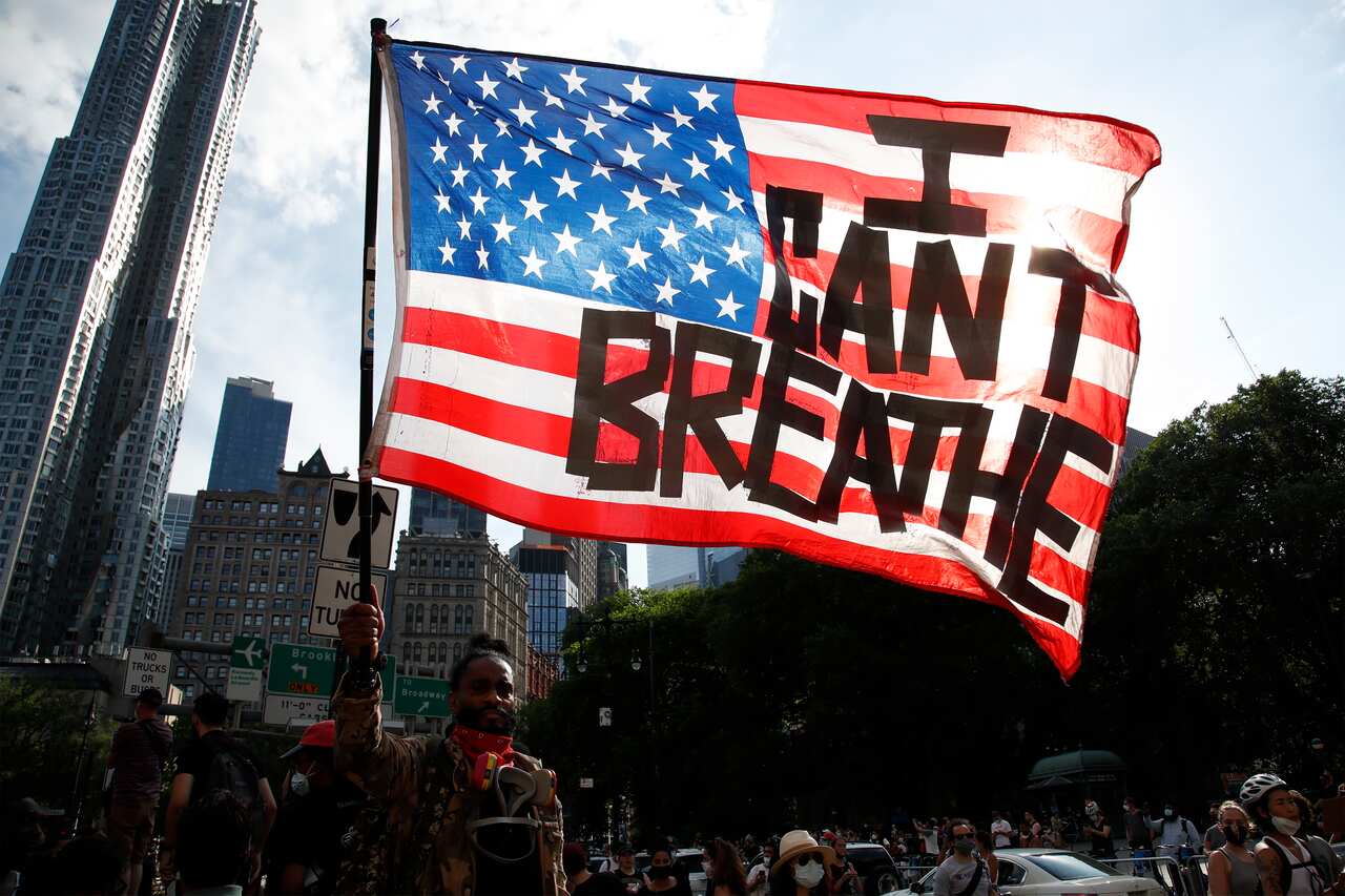 A protester holds an American Flag with the words 'I Can't Breathe' as he walks in Manhattan after a George Floyd Memorial demonstration in Brooklyn.