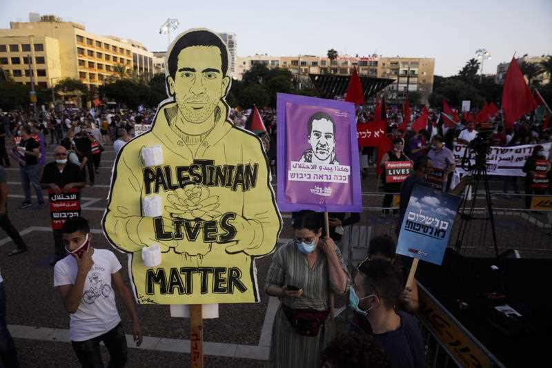 Protesters attend a rally in Tel Aviv holding a drawing representing Eyad Hallaq. 