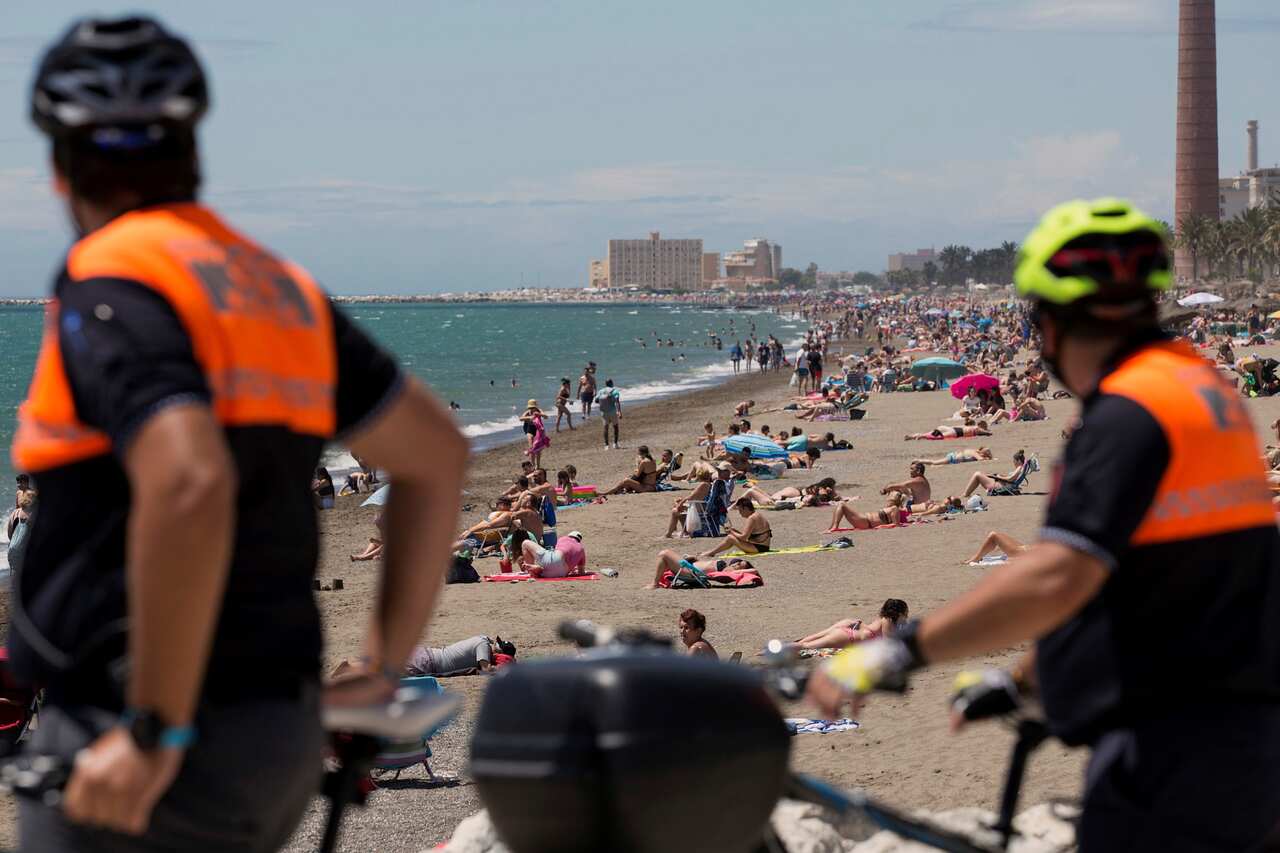 Bicycle-riding Civil Protection officers stay alert as beachgoers bask in the sun on a sultry day at La Misericordia beach in Malaga, southern Spain. 