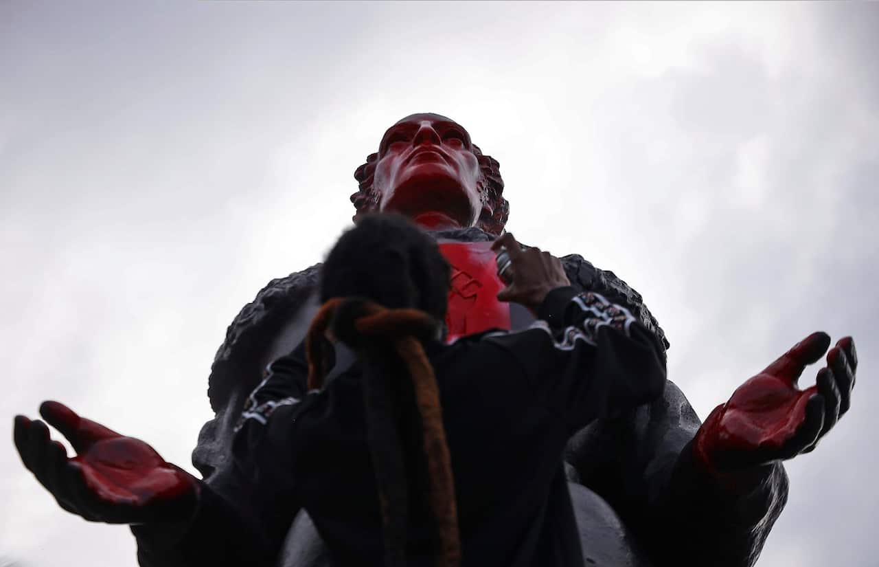 Protester spray paints the face of the statue of Christopher Columbus in Miami.