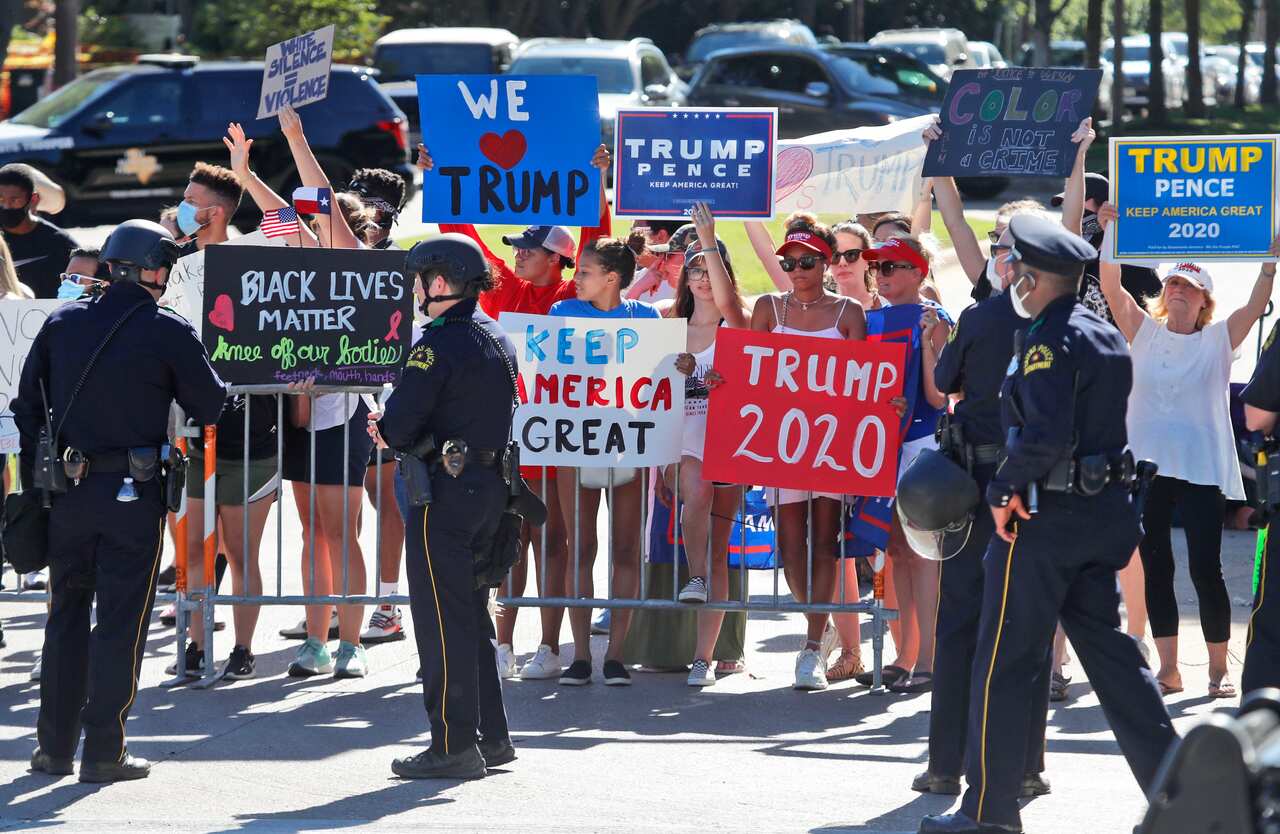 Police stand guard as people gather at a barricade trying to get a look at the arrival of President Donald Trump during a fund raising trip in Dallas.
