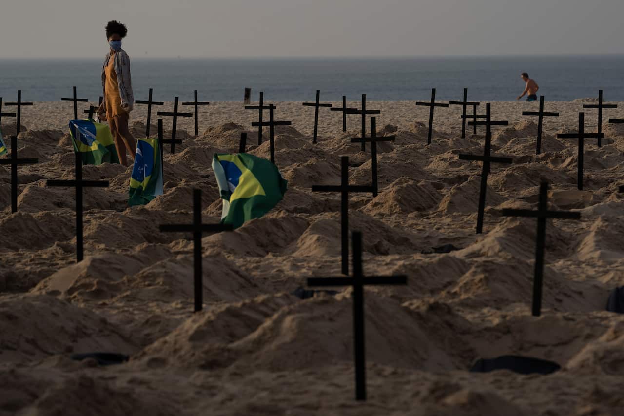 A woman walks amid symbolic graves on Copacabana beach, dug by activists from NGO Rio de Paz protesting Brazil's handling of the COVID-19 pandemic.
