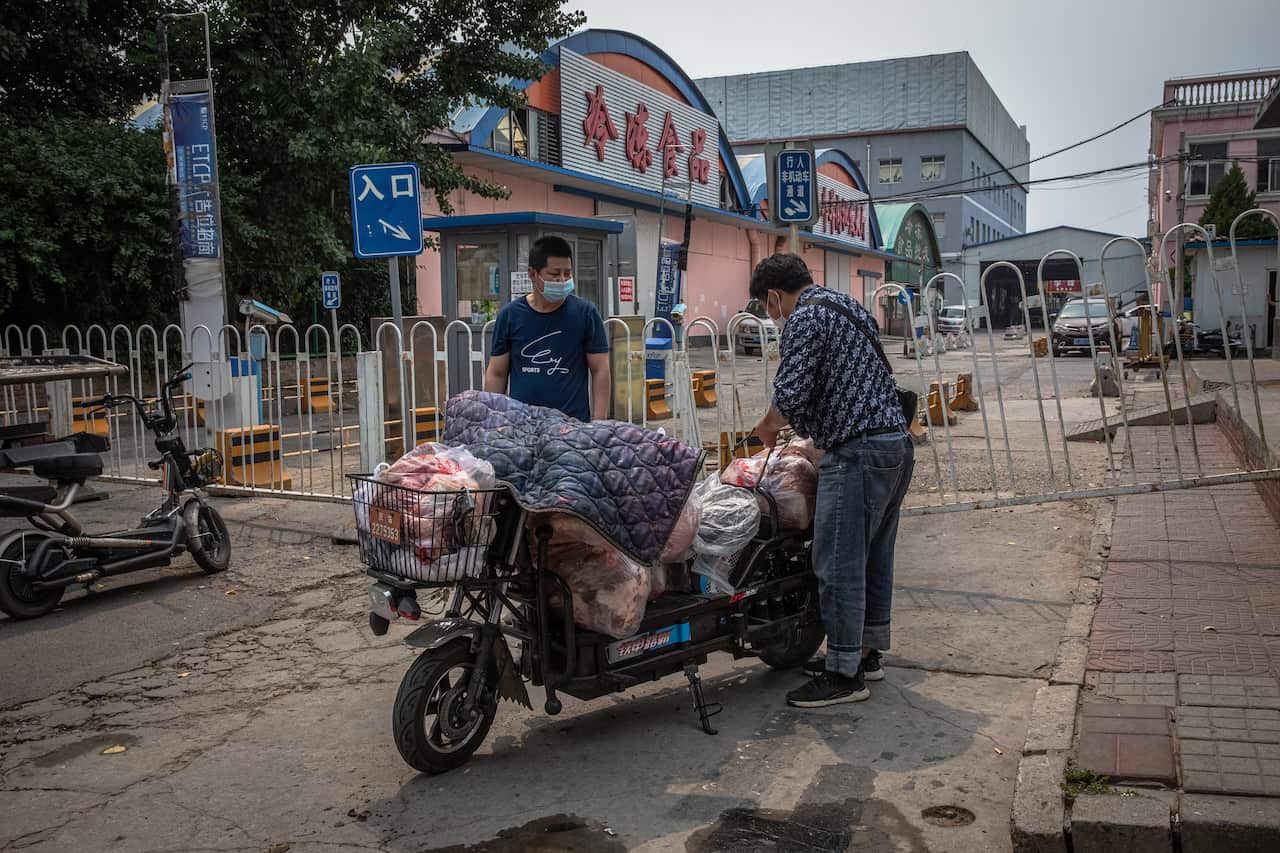 Men wearing protective face masks load a scooter with meat next next to the closed Xinfadi market in Beijing, China.