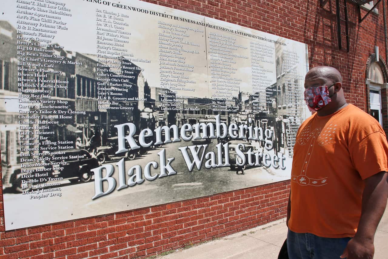 Freeman Culver stands in front of a mural listing the names of businesses destroyed during the 1921 Tulsa race massacre in Tulsa, Oklahoma.