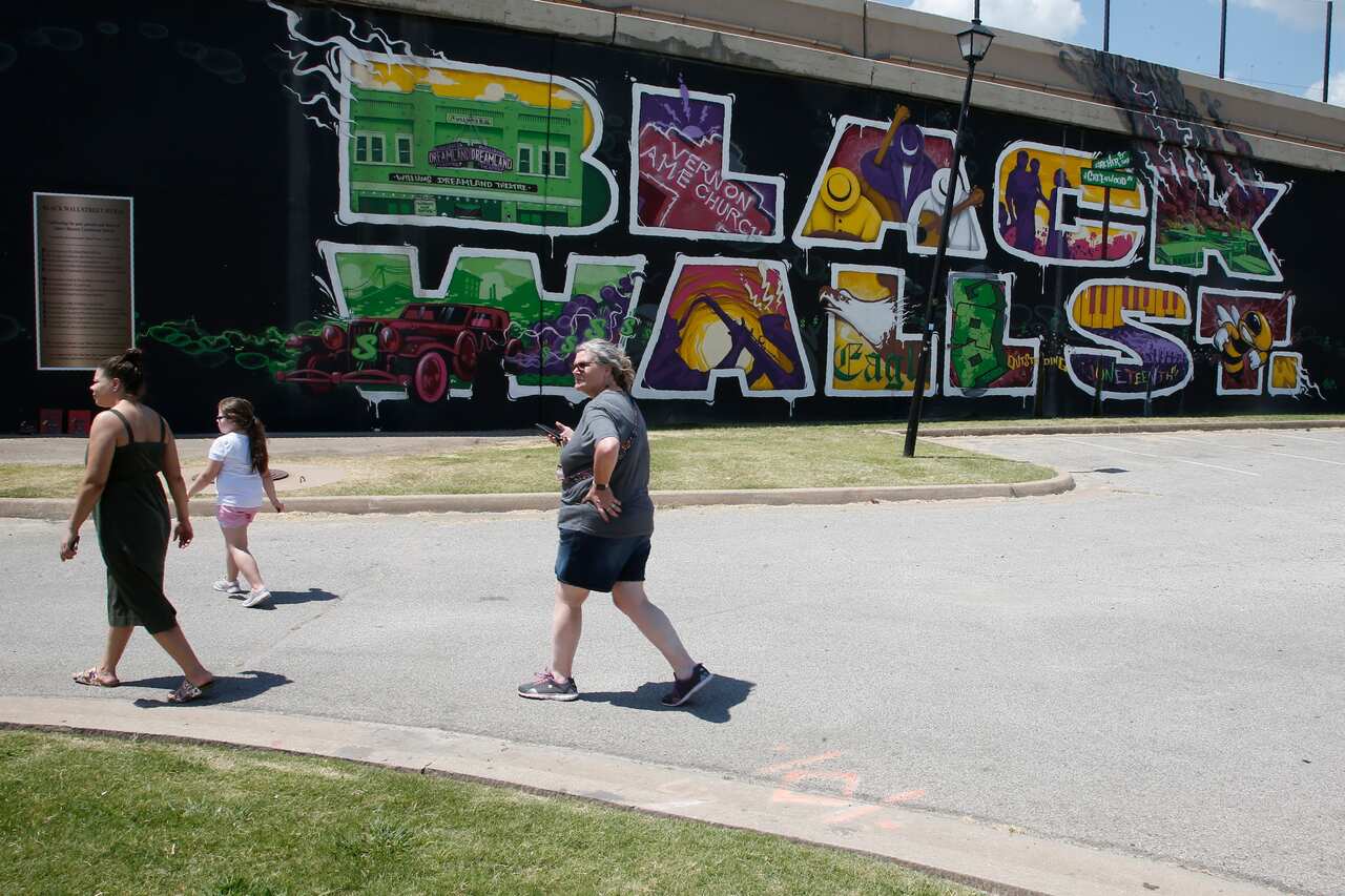 People walk past a Black Wall Street mural in the Greenwood district in Tulsa, Oklahoma.