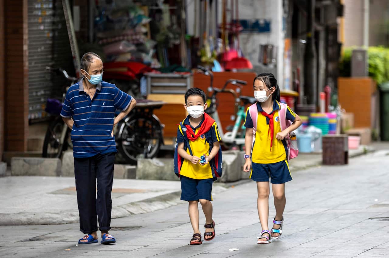 A grandfather walks children home from school in Guangzhou, China, 22 June 2020. 