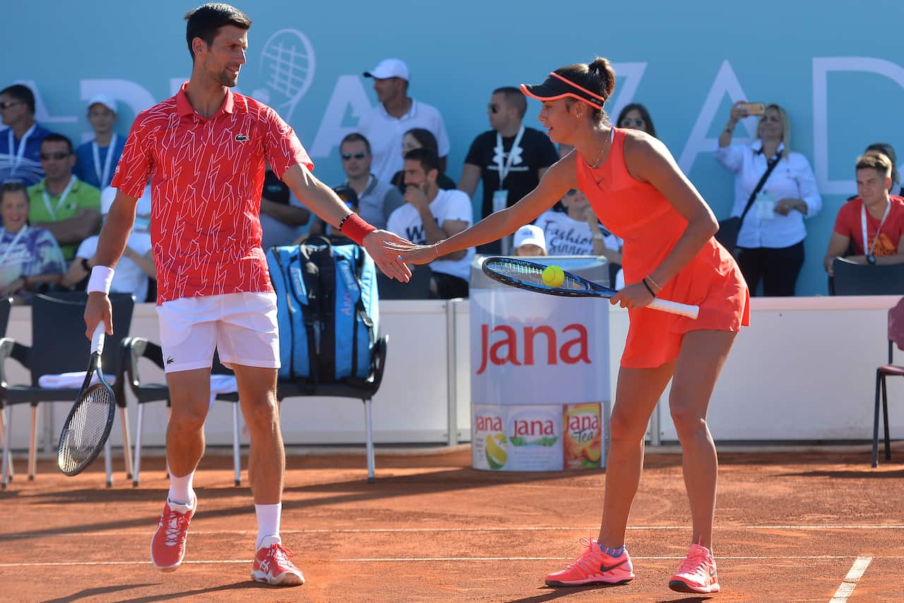 Serbian tennis player Novak Djokovic touches hands with Olga Danilovic during their mixed doubles match.