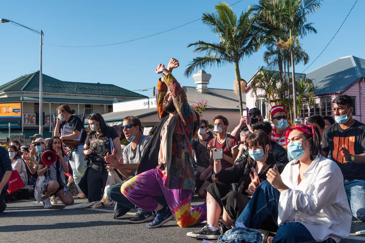 Protesters take a knee and show support to refugees being detained at a Brisbane hotel.