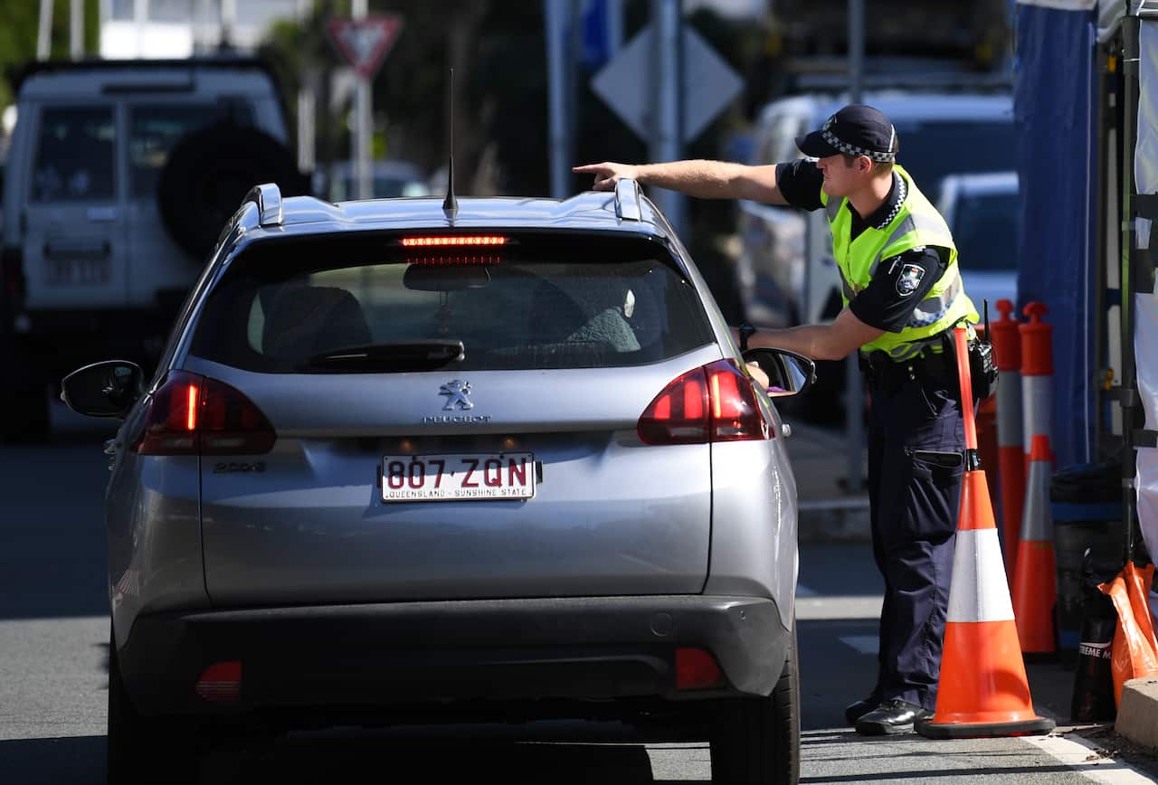 A police officer directs a car for further inspection at a check point on the Queensland-New South Wales.