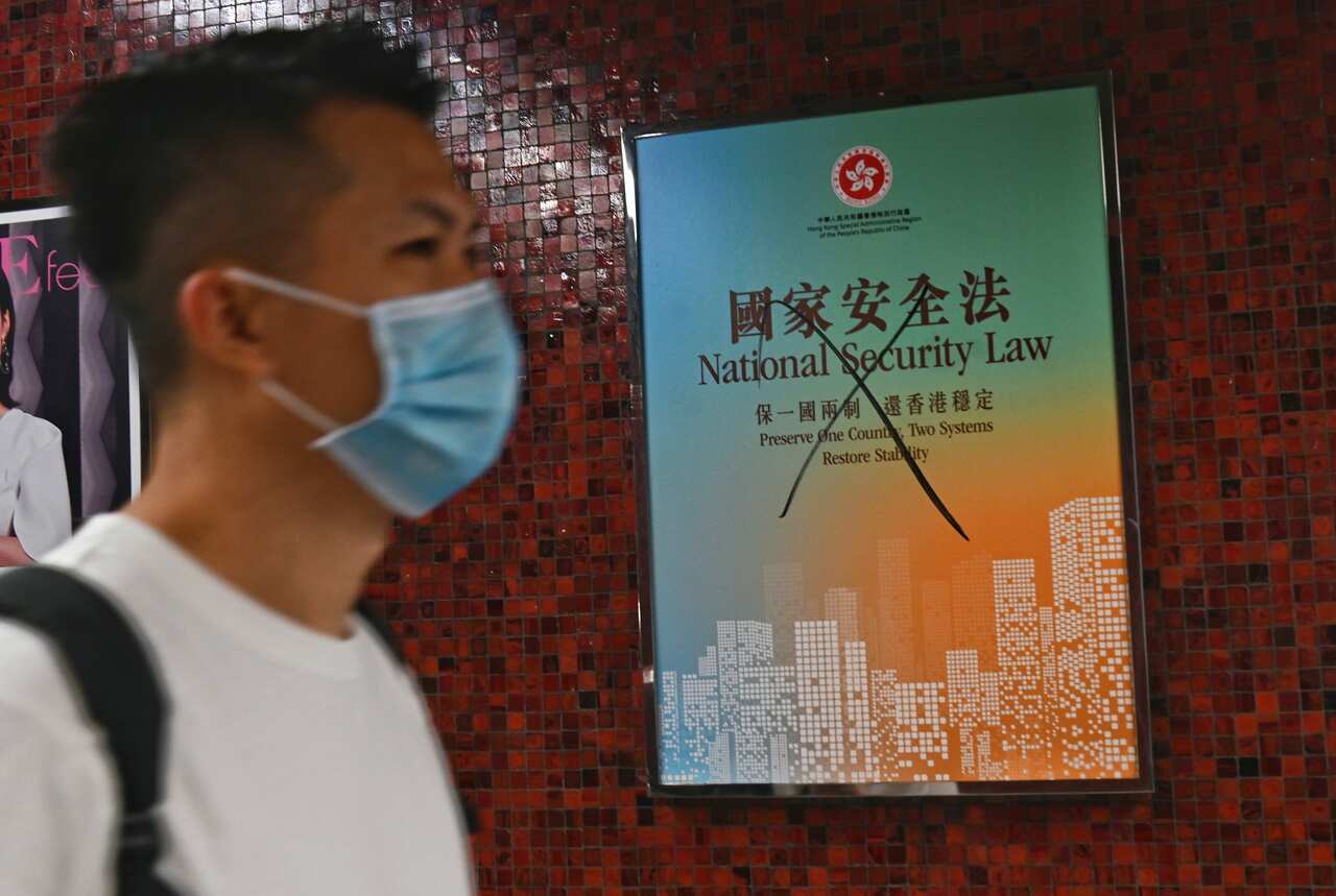 A commuter walks past a vandalised poster promoting the new national security law, in a subway station in Hong Kong, China, 1 July 2020