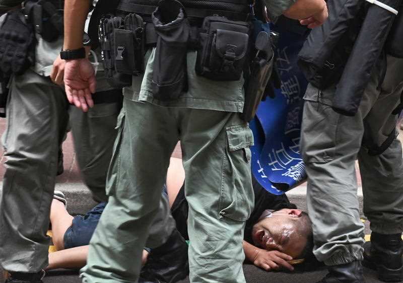 Hong Kong police officers detain a protester after he was pepper sprayed on 1 July, 2020
