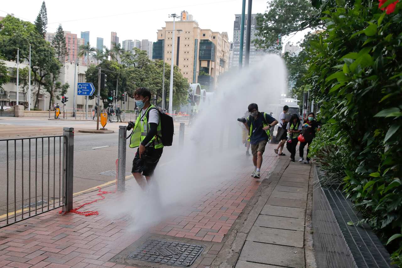 Journalists run as police fire water cannons during a march against the new national security law in Hong Kong.