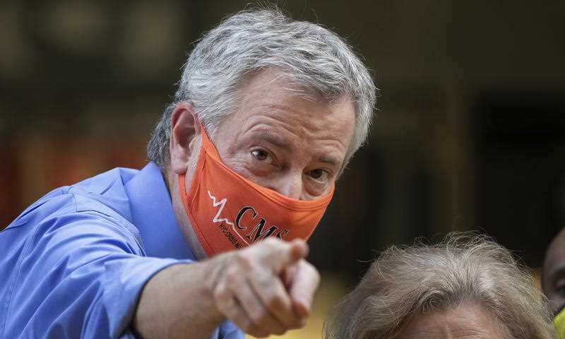 Mayor Bill de Blasio points to the crowd while painting Black Lives Matter on Fifth Avenue in front of Trump Tower, Thursday, July 9, 2020, in New York.