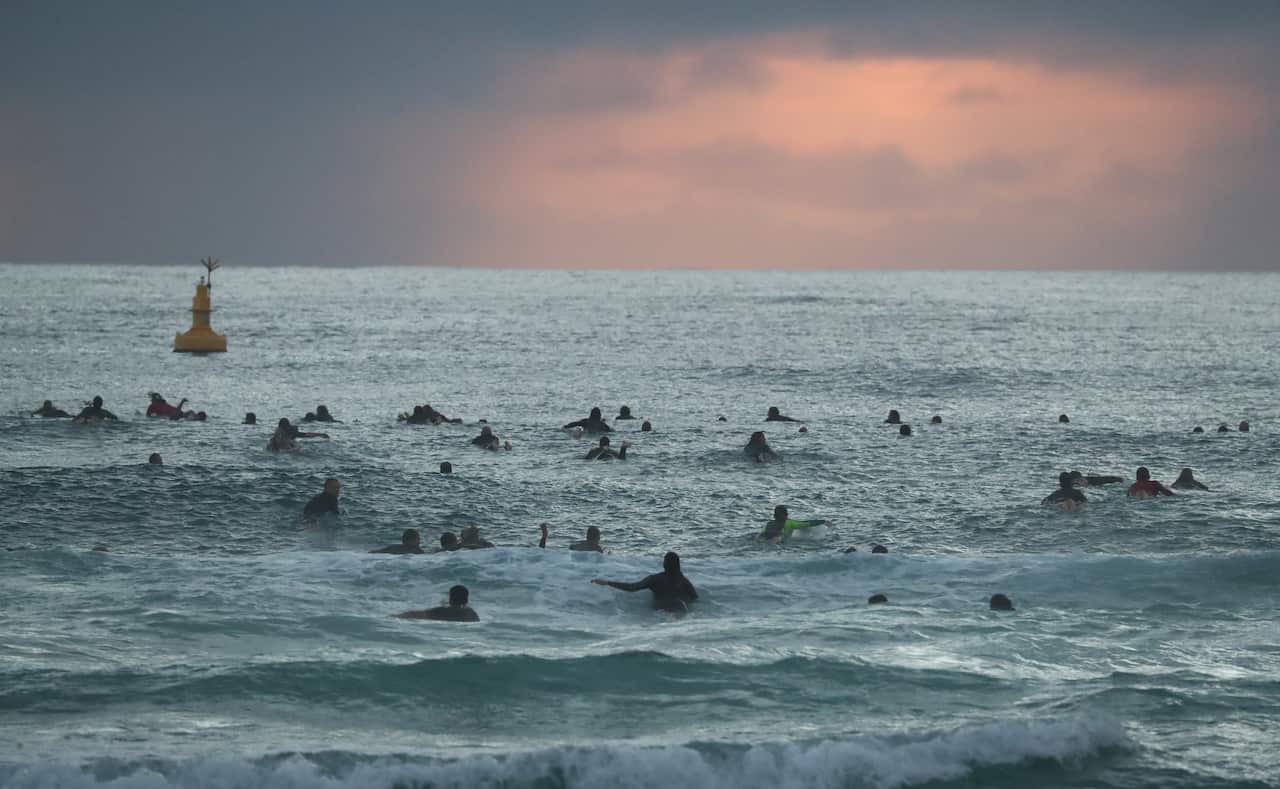 Friends, family, and community members swim out in the early morning during the 'Paddle Out For Chumpy'