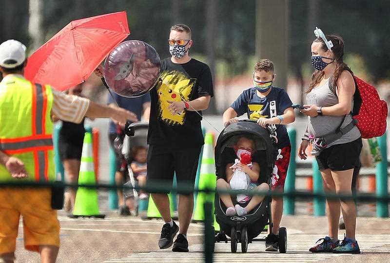 Guests wearing masks walk to the entrance of Walt Disney World's Magic Kingdom in Orlando, Florida, on Saturday, July 11, 2020.