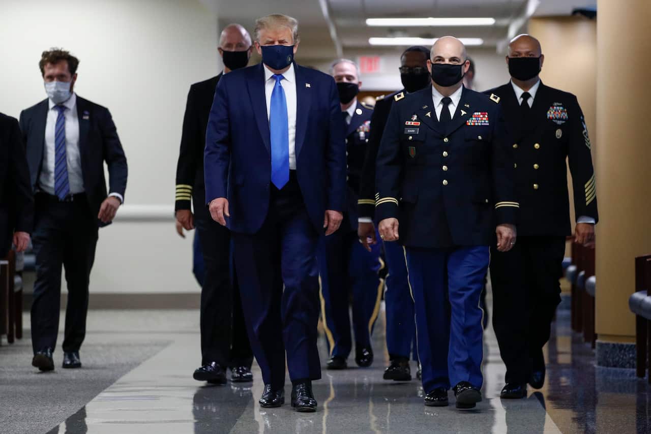 President Donald Trump wears a mask as he walks down the hallway during his visit to Walter Reed National Military Medical Centre