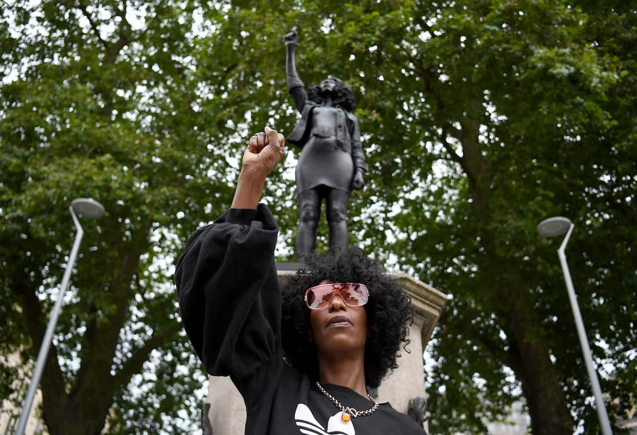 B;ack Lives Matter protester Jen Reid poses in front of a statue of herself.