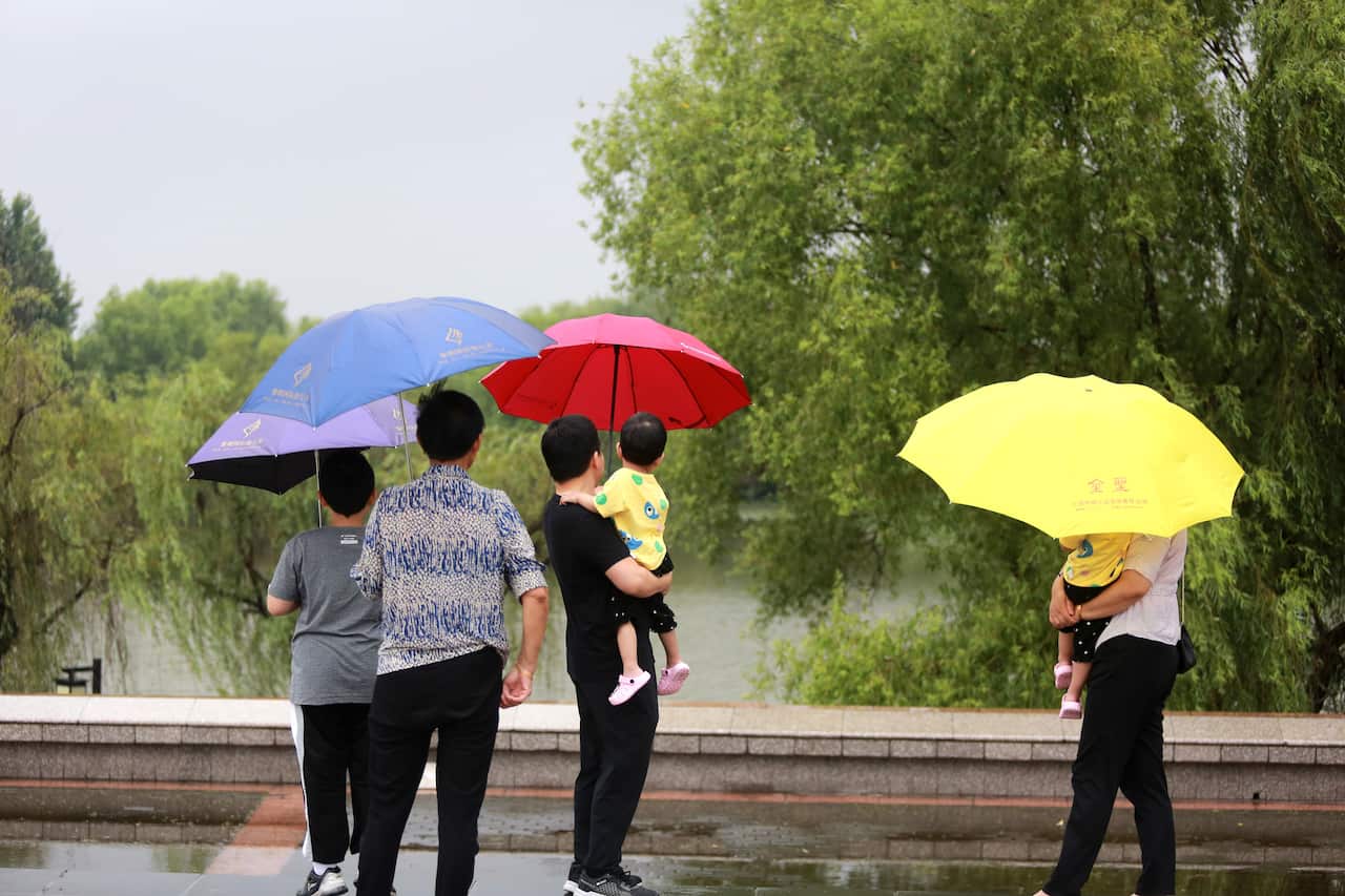 People watch the river rise at the bank next to the Yangtze River Park.