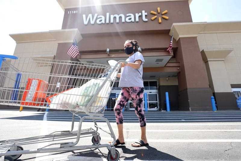 A Walmart shopper wears a mask as protection against the coronavirus as she exits a Walmart Supercenter in Fairfax, Virginia.