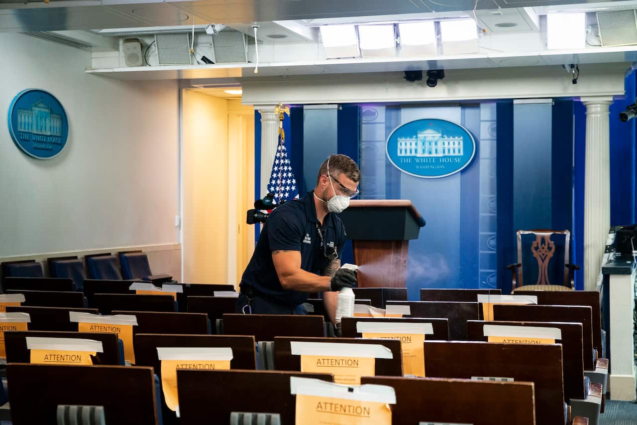 A worker sprays seats with disinfectant before a news conference at the White House.