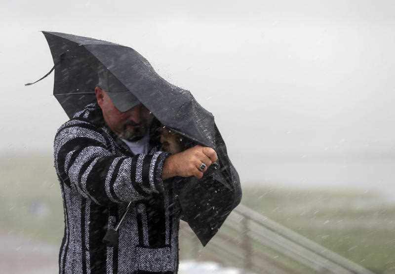 A man fights heavy rain and wind on Seawall Boulevard, Saturday, July 25, 2020