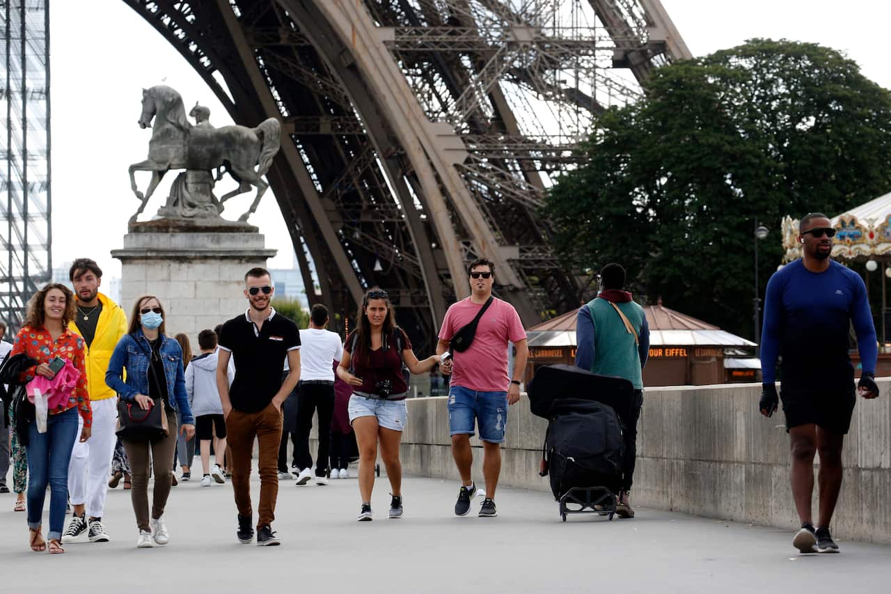 People walk next to the Eiffel Tower in Paris.