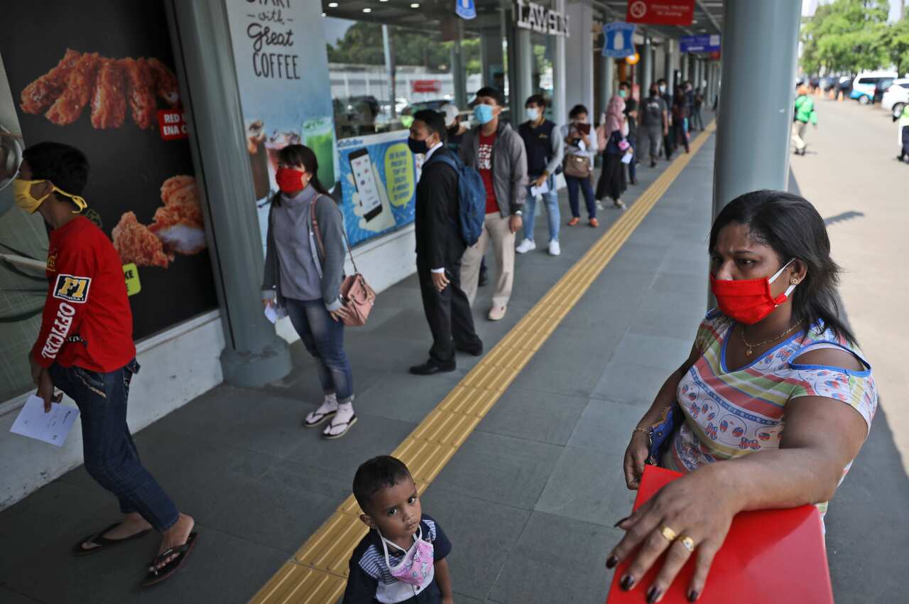 A woman and her son wait as people queue up for coronavirus test in Jakarta, Indonesia.