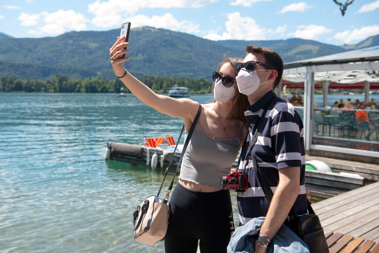 A young couple take selfies at the lake side in St. Wolfgang, Austria.