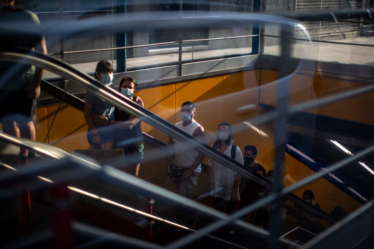 People wearing face mask to prevent the spread of coronavirus use the escalator inside a subway in Madrid, Spain. 