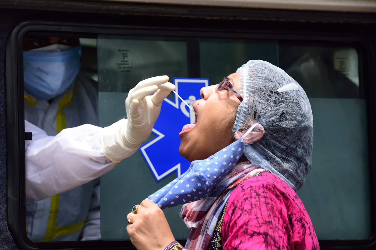 A health worker takes a mouth swab from a woman during community swab testing in Kolkata, India.