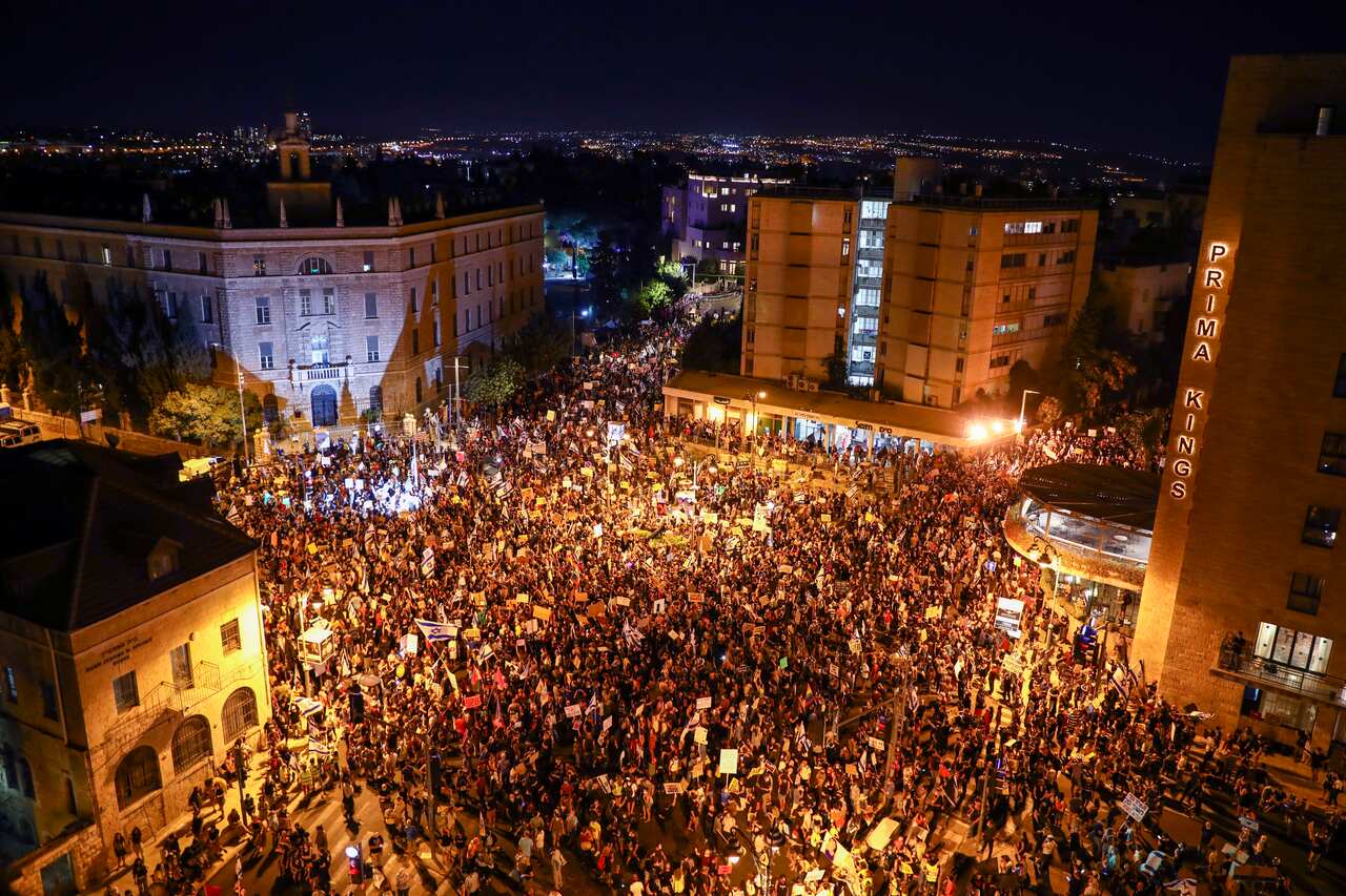 Thousands of protesters chant slogans and hold signs during a protest outside the Jerusalem residence of  Israel's Prime Minister Benjamin Netanyahu.