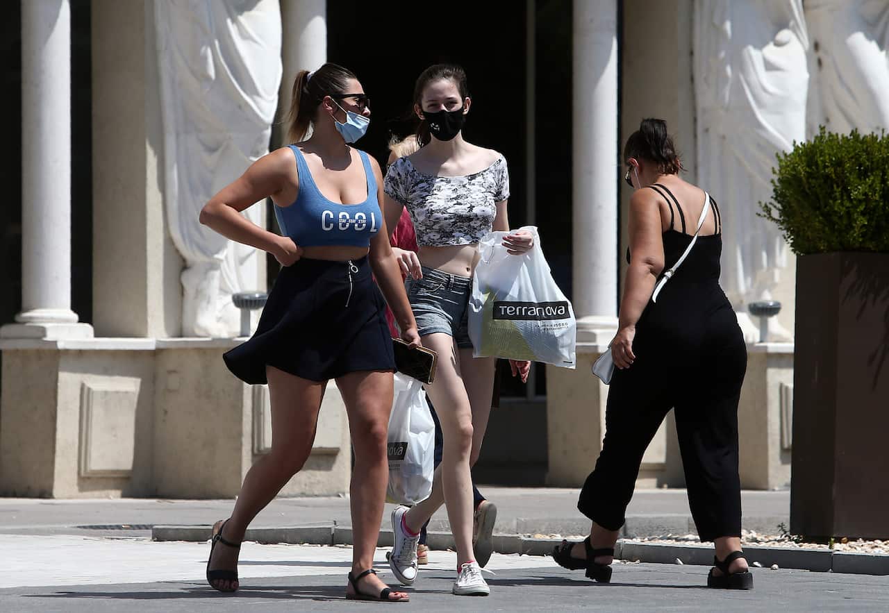 Young women wearing face masks walk through a street in downtown Skopje, North Macedonia.