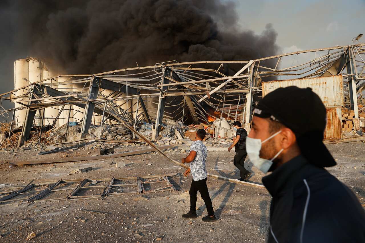 Lebanese port workers walk at the explosion scene that hit the seaport of Beirut, Lebanon, Tuesday, 4 August, 2020. 