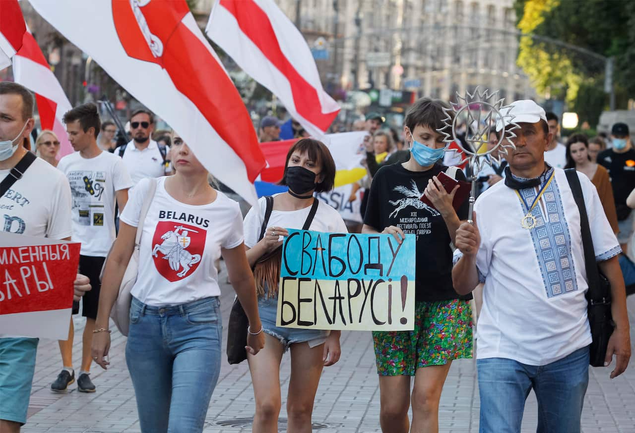Belarusian citizens in Ukraine hold Belarusian flags during a rally in solidarity with the country's opposition.