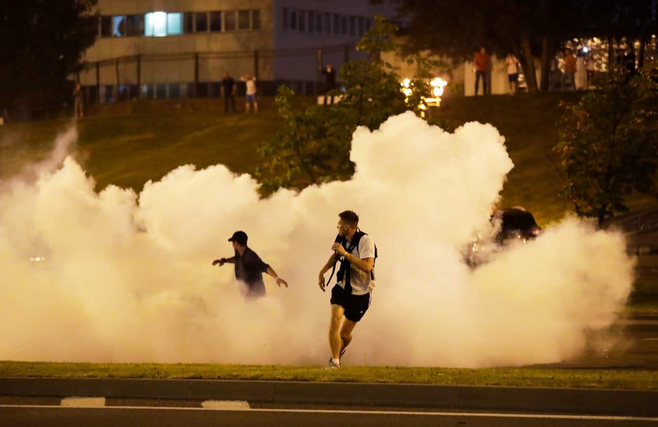 Protesters run through smoke during mass protests after the Belarusian presidential election in Minsk, Belarus.