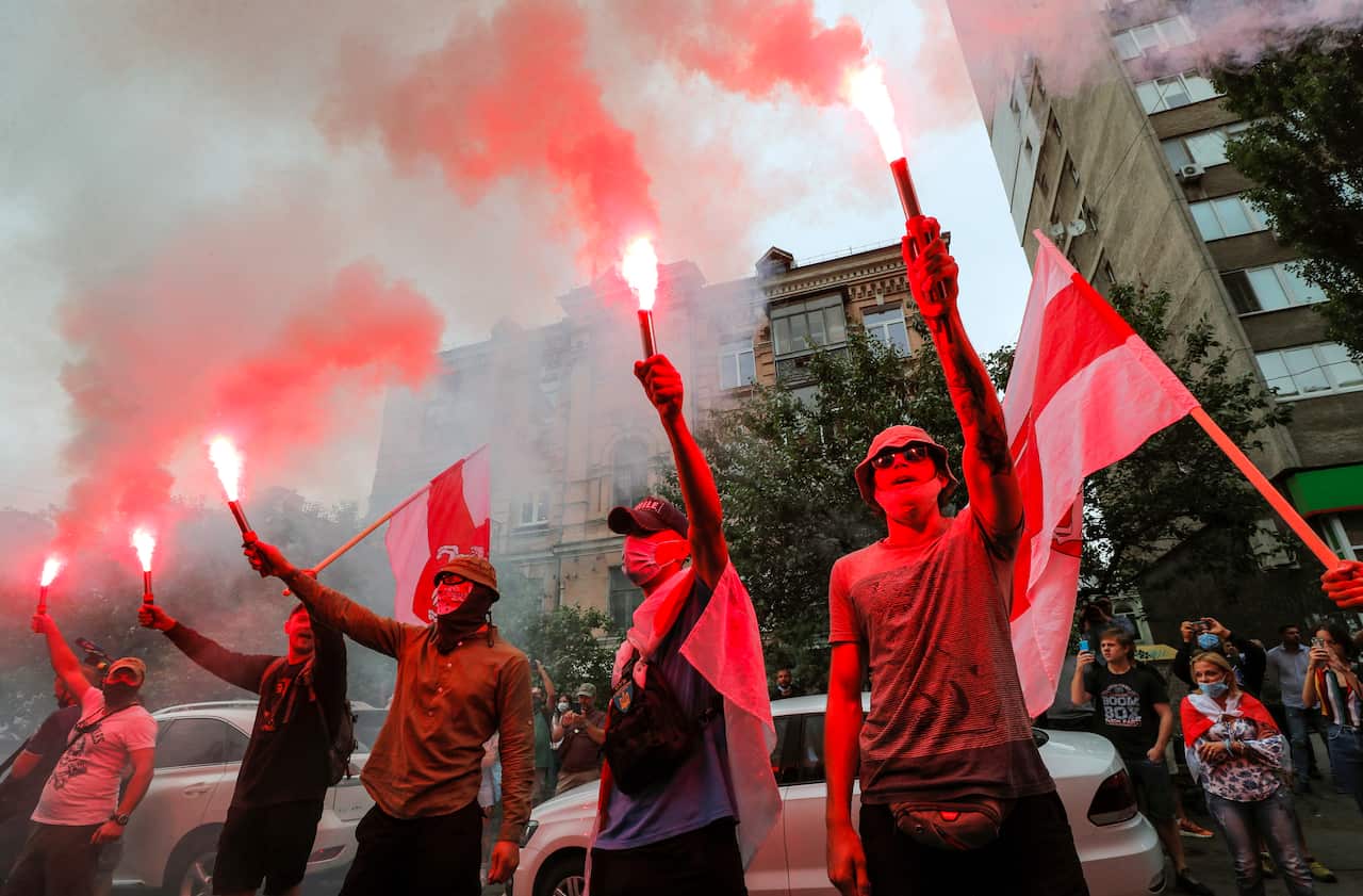 Belarusians who live in Ukraine burn flares during their rally against the election results.