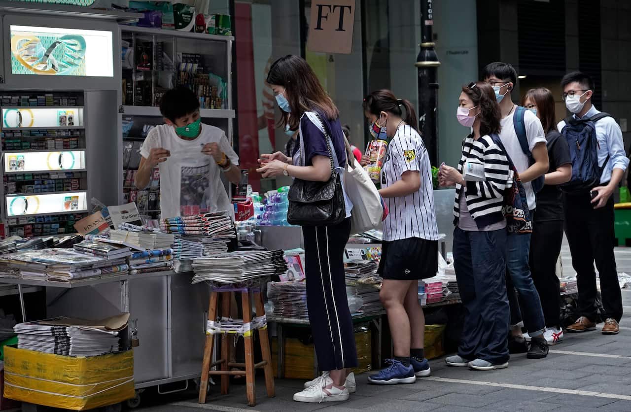 People queue up at a news stand to buy copies of Apple Daily at a downtown street in Hong Kong.