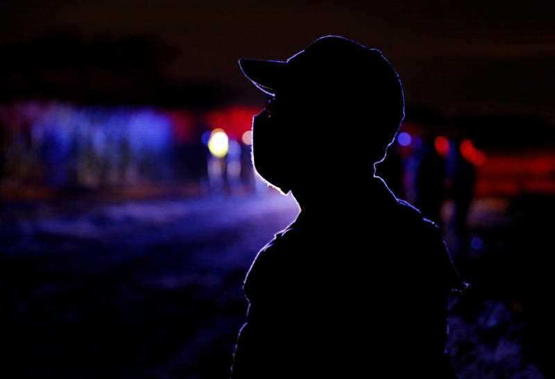 Police officers provide security at the place where five young people were murdered the night before, in Cali, Colombia, 12 August 2020.