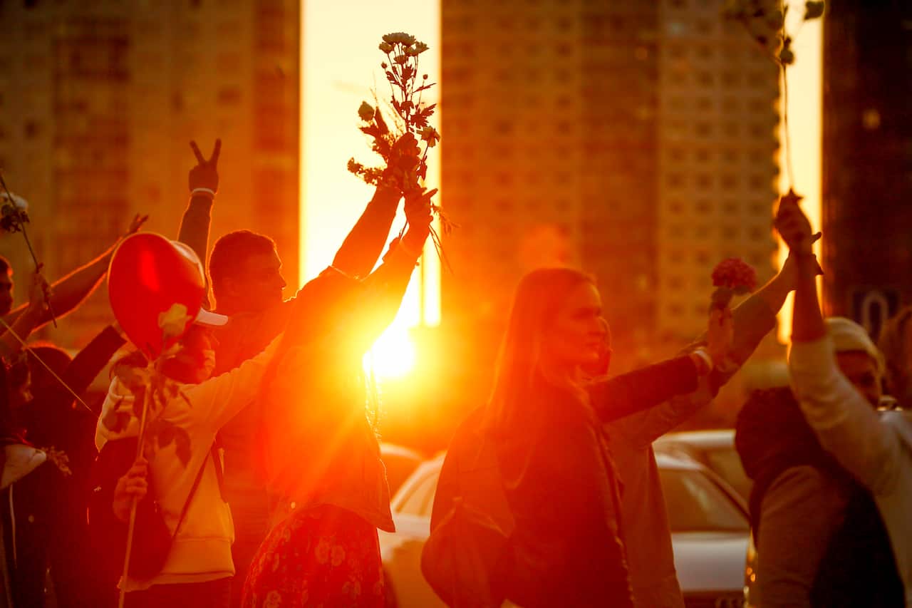 People wave flowers as they gather to protest during sunset in Minsk, Belarus, on 13 August.