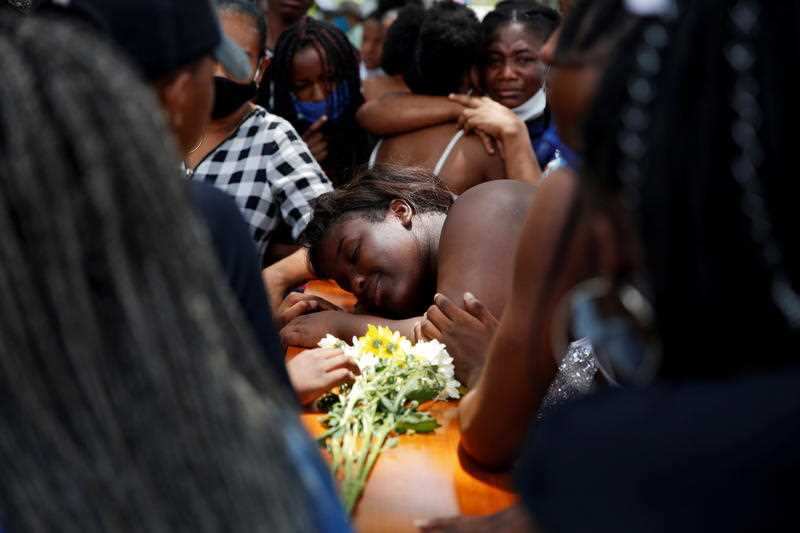  A woman stands on a coffin during the funeral of the five young men murdered this week, in Cali, Colombia, 13 August 2020. 