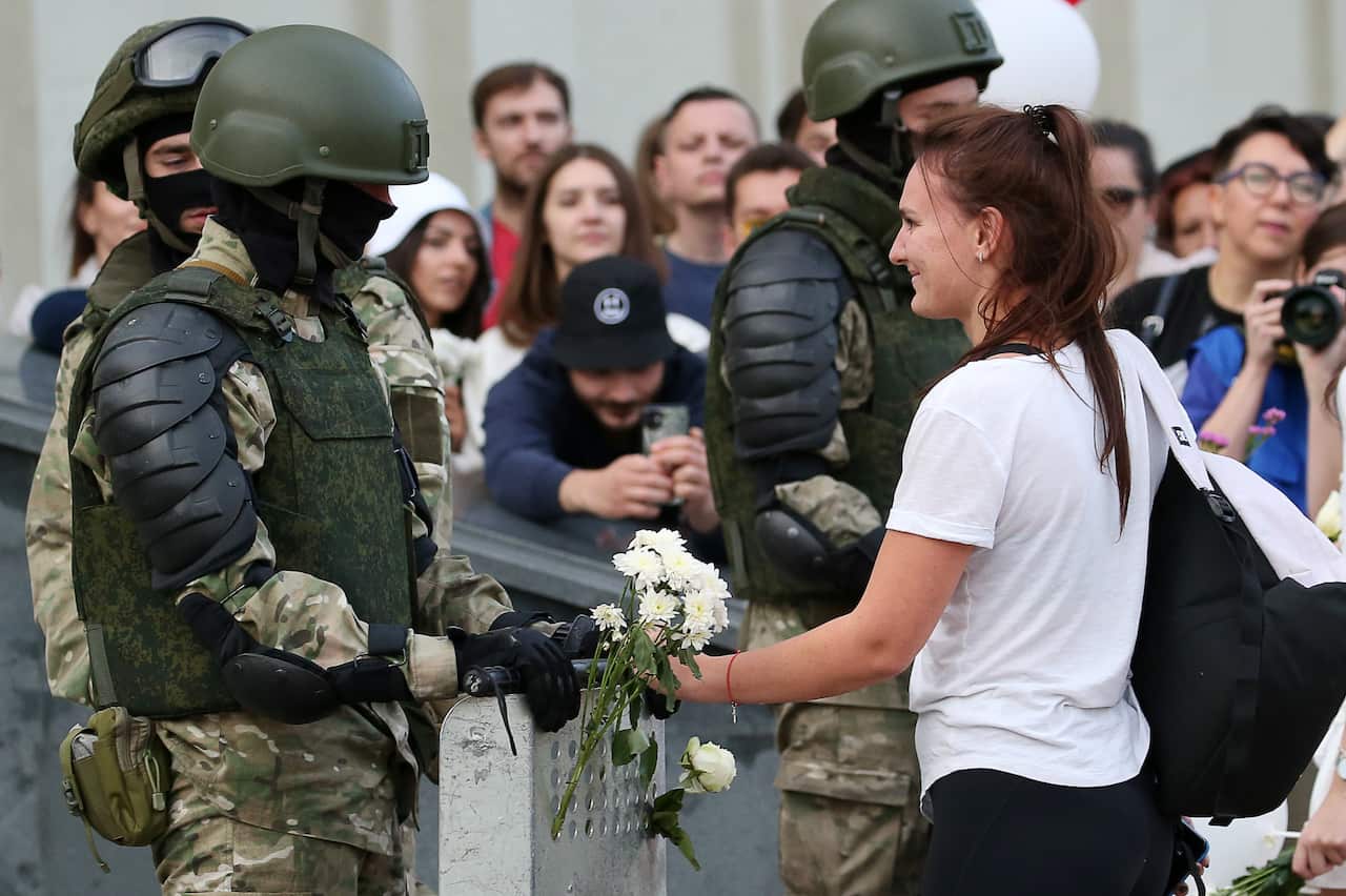 A woman puts a flower into a shield put down by a Belarusian law enforcement officer in solidarity with protesters in Minsk, Belarus, on 14 August.