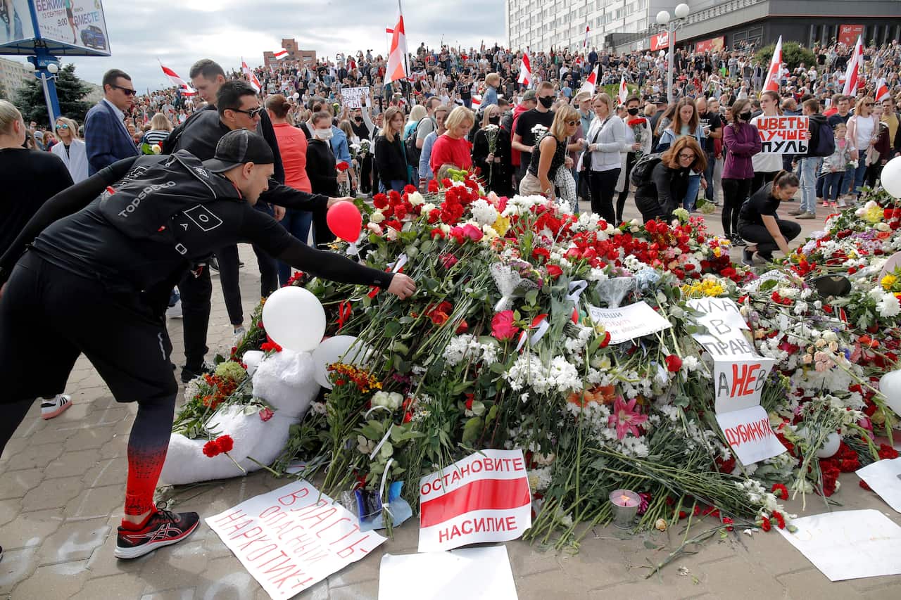 People lay flowers as they gather at the place where Alexander Taraikovsky died during his civil funeral in Minsk, Belarus on 15 August.