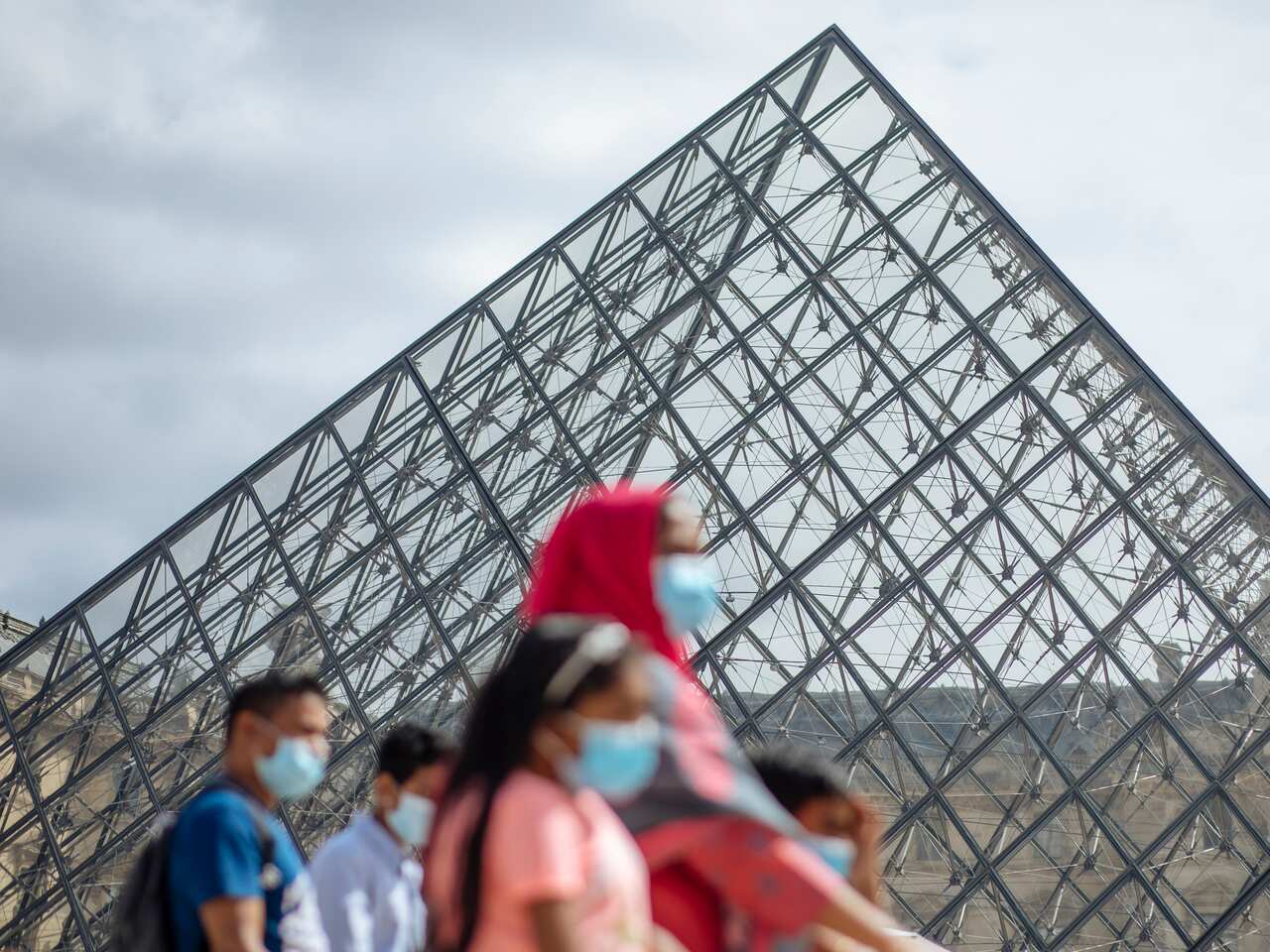 A family wearing face masks walk past the Louvre Museum in Paris on 15 August.
