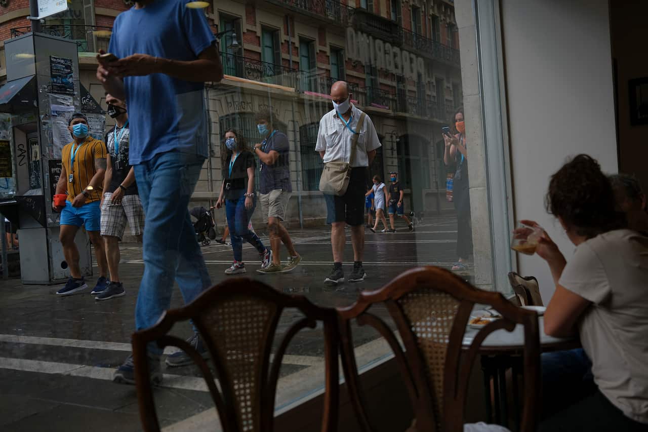 People gather in a bar to drink a coffee while pedestrians walk past wearing face masks in Pamplona, northern Spain, on 15 August.
