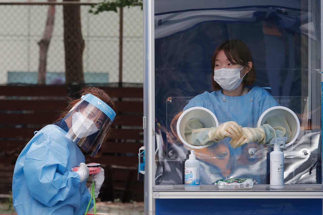 A medical worker holds a portable fan amid the sweltering heat during police officers the COVID-19 testing at a makeshift clinic in Seoul, South Kore