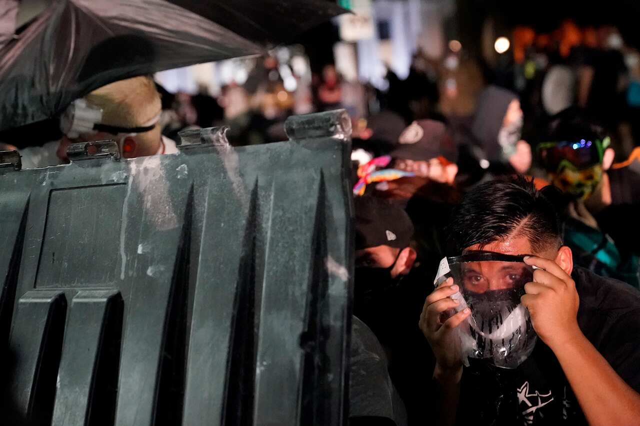 A protester takes cover during clashes outside the Kenosha County Courthouse.