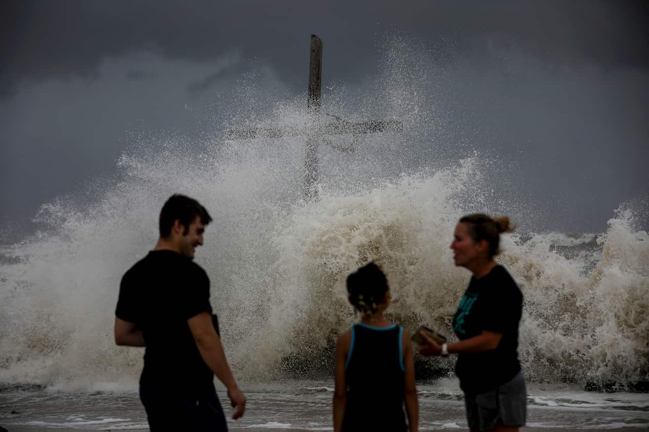 People talk as waves wash ashore and the outer bands of Hurricane Laura bring winds and rain Wednesday, Aug. 26, 2020, in High Island. ( Jon Shapley/Houston Chronicle via AP)